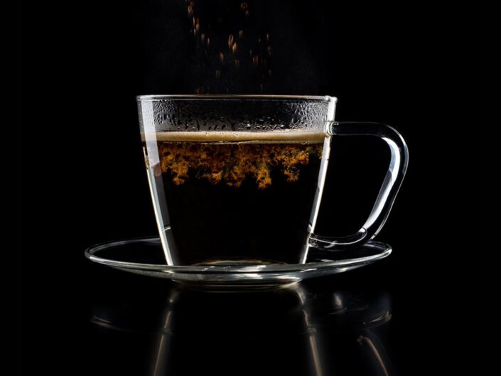 Löffel lässt Teeblätter in heißes Wasser gleiten