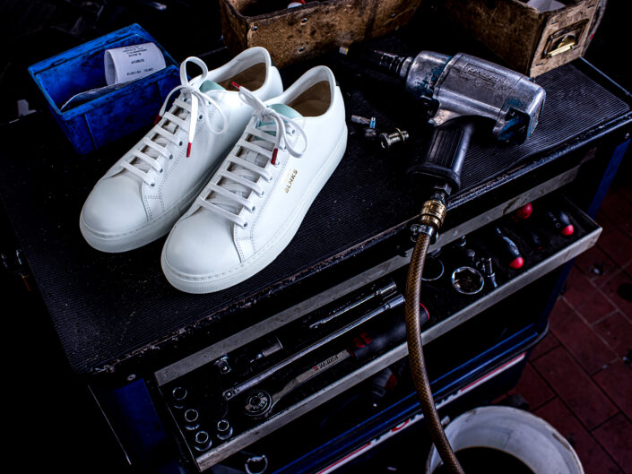 weiße Blnks Sneaker auf Werkzeugtisch, Reparaturwerkstatt, Werkzeuge