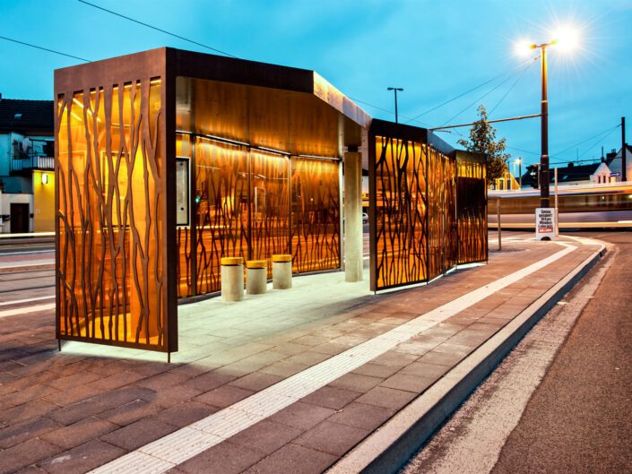 Bahnhofspavillon: Moderner Pavillon mit Glas- und Holzdesign Nachtaufnahme mit stimmungsvoller Beleuchtung Transparente Glaswände für klare Sicht auf das Innere Kombination aus Funktionalität und ästhetischem Design