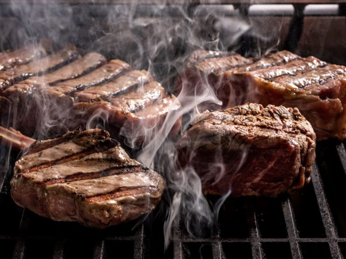 Steaks auf dem Grillrost mit Rauch.