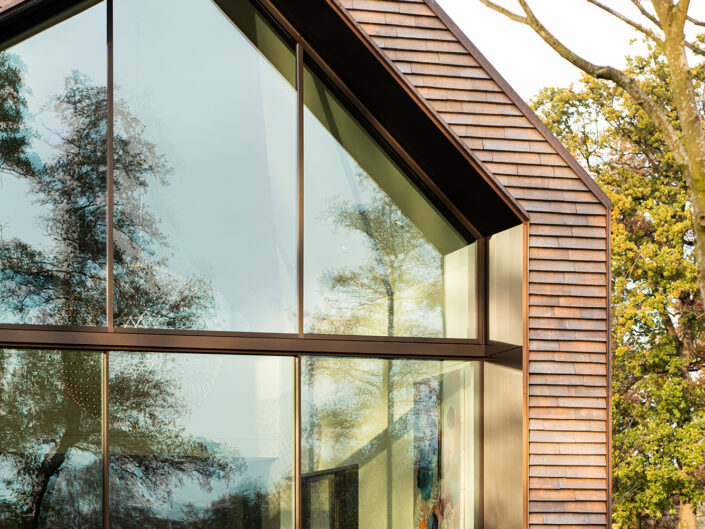 Haus mit unüblichem Winkel, Großes Fenster: Großflächige Glasfenster mit Ausblick auf Bäume und die Natur Minimalistischer Rahmen und klare Linien für ein modernes Design Nahtlose Verbindung zwischen Innen- und Außenbereich, Architektur, Architektur Photographie